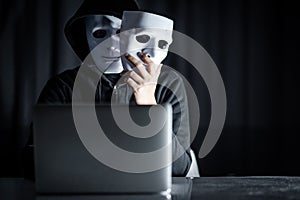 Mystery male hacker holding white mask
