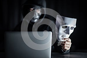 Mystery man in black mask holding white mask