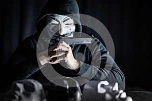 Mystery man holding gun over masks on table