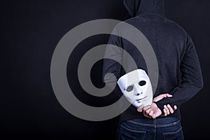 Mystery man holding white mask in the back