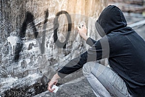 Mystery man in hoody spraying word on the wall