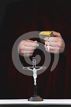 Mystery monk's hands with a cape, bible, a black rosary and cr