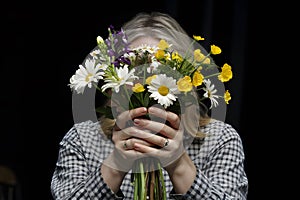 Mystery person with vibrant flowers and checkered shirt, rings on fingers