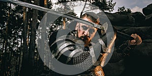 Mystery scarface knight in armor with sword and crossbow in the forest