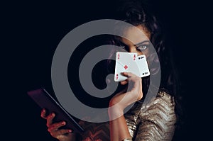 Mystic beautiful girl, covering face with cards and holding tablet in hand, online poker concept