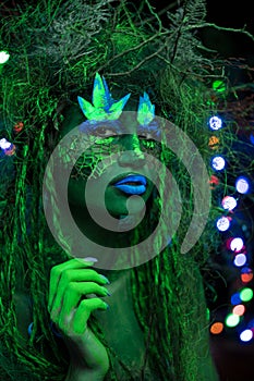 Mystic green dryad in UV fluor black light with Glowing trees on background