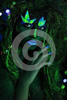 Mystic green dryad in UV fluor black light with Glowing trees on background