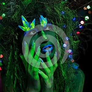 Mystic green dryad in UV fluor black light with Glowing trees on background