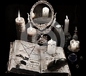 Mystic still life with black magic book, candles and mirrow