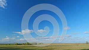 Mystic white clouds flying over green autumn field. Clouds fly across the blue sky. Timelapse.