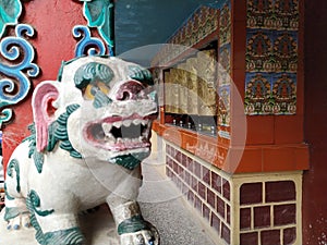 Mystical creature in a buddhist monastery. A white lion and prayer wheels.