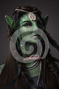 Mystical enchantress elf with green skin against grey background