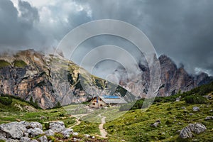 Mystical landscape with rocky mountains and house in the fog in cloudy weather, Italian alps. Tre Cime park in Dolomites