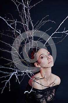 Mystical portrait of an Armenian woman with big blue eyes and branches behind. Lovely gorgeous girl posing in evening dress