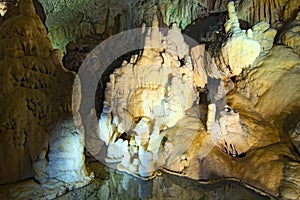 Mystical view of Postojna Cave. Ancient formations inside cave with stalactites and stalagmites. Famous touristic place