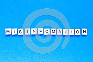 Mystification written in wooden letters on a blue background, top view, flat layout, deception, fake information, fake news
