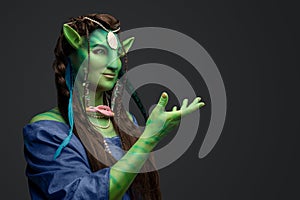 Mythical female elf with green skin and outstretched arm