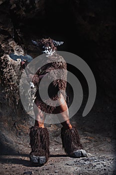 Mythological Minotaur  half bull half man stands in a rock cave in an aggressive stance