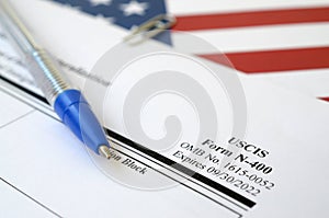 N-400 Application for Naturalization blank form lies on United States flag with blue pen from Department of Homeland Security