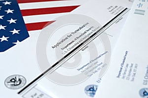 N-400 Application for Naturalization blank form lies on United States flag with envelope from Department of Homeland Security