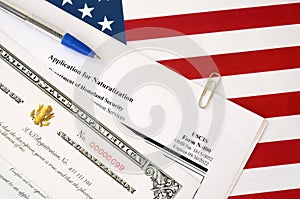 N-400 Application for Naturalization and Certificate of naturalization lies on United States flag with blue pen from Department of