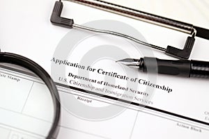 N-600 Application for Certificate of Citizenship blank form on A4 tablet lies on office table with pen and magnifying