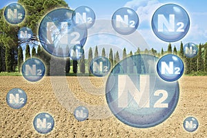 N2 nitrogen gas is the main constituent of the earth`s atmosphere - concept with nitrogen molecules against a natural rural scene