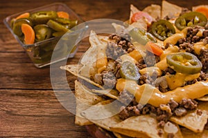 Nacho chips corn garnished with ground beef, melted cheese, jalapeÃ±os peppers, mexican spicy food in mexic