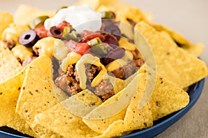 Nachos with beef, jalapeno peppers, olives, tomato, beans, cheese and sour cream