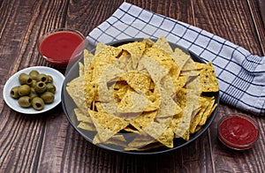Nachos in a bowl with tomato sauce and olives. Tortilla chips isolated on white background