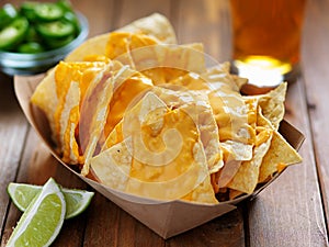 Nachos and cheese in tray with beer