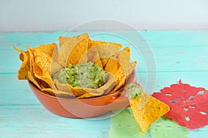 Nachos with guacamole on blue wooden background.