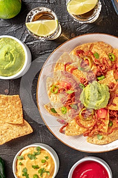 Nachos, shot from above with tequila and various dips, Mexican food and drink