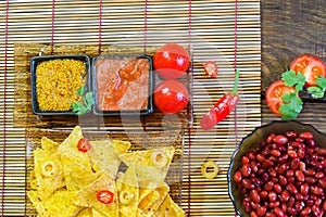 Nachos top view with Tortilla chips tomato salsa and mustard on rustic wooden background. A textured background.Copy paste place