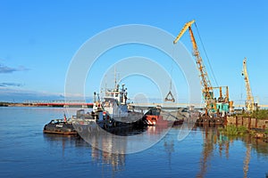 A tug with a barge and a floating crane at the pier in the port of Nadym in Siberia