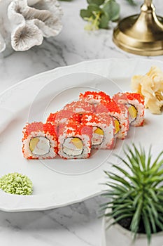 Nagiri Sushi roll with caviar ,shrimps,  cheese and mango in the white plate on light marble background. Healthy sea food, hard