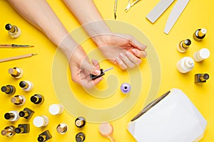 Nail art in the luxurious beauty salon. Gel for modeling nails. A woman receives a manicure by a beautician. On a yellow