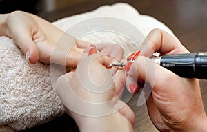 Nail artist saws and attaches a nail shape during the procedure of nail extensions with gel in the beauty salon
