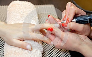 Nail artist saws and attaches a nail shape during the procedure of nail extensions with gel in the beauty salon.
