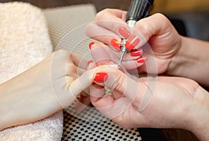 Nail artist saws and attaches a nail shape during the procedure of nail extensions with gel in the beauty salon.