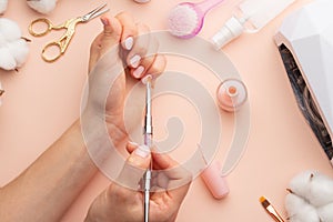 Nail care. beautiful women hands making nails painted with pink gentle nail polish on a pink background. Women`s hands near a set