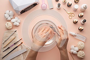 Nail care. beautiful women hands making nails painted with pink gentle nail polish on a pink background. Women`s hands near a set