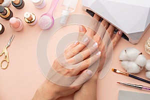Nail care. beautiful women hands making nails painted with pink gentle nail polish on a pink background. Women`s hands near a set