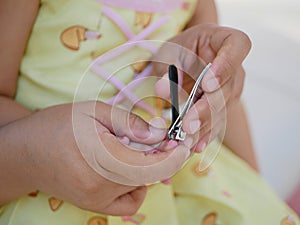 A nail clippers in mother`s hand trimming her baby girl`s fingernails - cutting baby`s nails