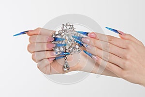 Nail Polish. Art Manicure. Modern style blue Nail Polish. Beauty hands holding white crystals gem stones diamonds broach showing