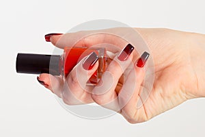 Nail Polish. Art Manicure. Modern style red black gradient Nail Polish. Beauty hands holding red bottle. Stylish Colorful trendy