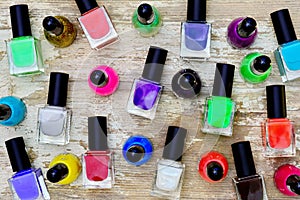 Nail polish bottles of different colors on white wooden table.