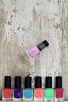 Nail polish bottles of different colors on white wooden table.