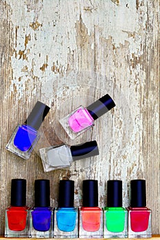 Nail polish bottles of different colors on white wooden table.