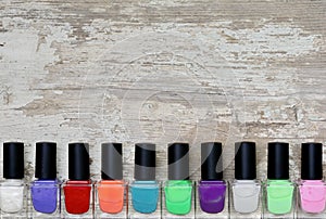 Nail polish bottles of different colors on white wooden table.